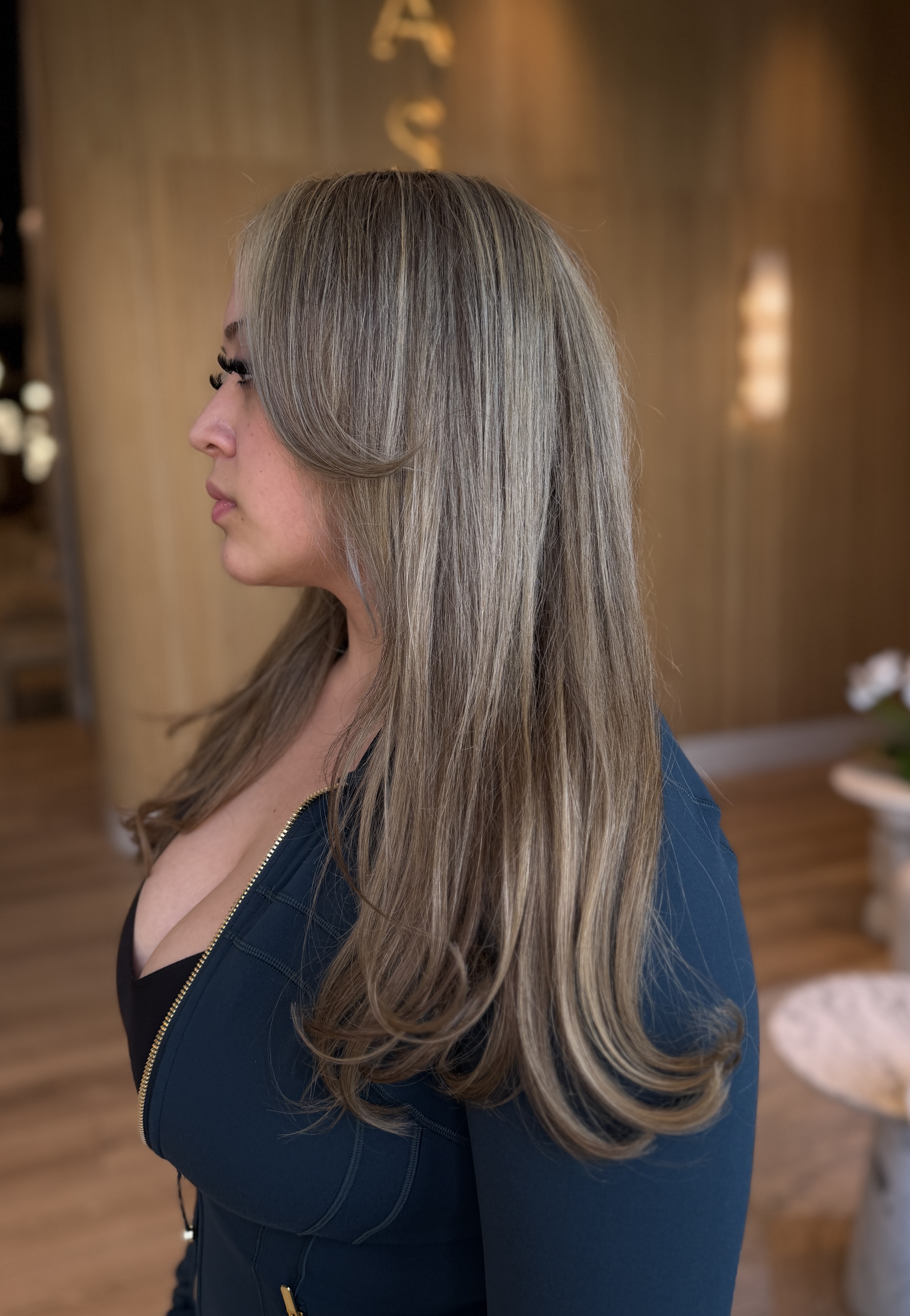 Ash-blonde balayage blend on dark roots, sleek side profile showing natural dimension — cruelty-free color near Rialto & Ontario, Likha Studio