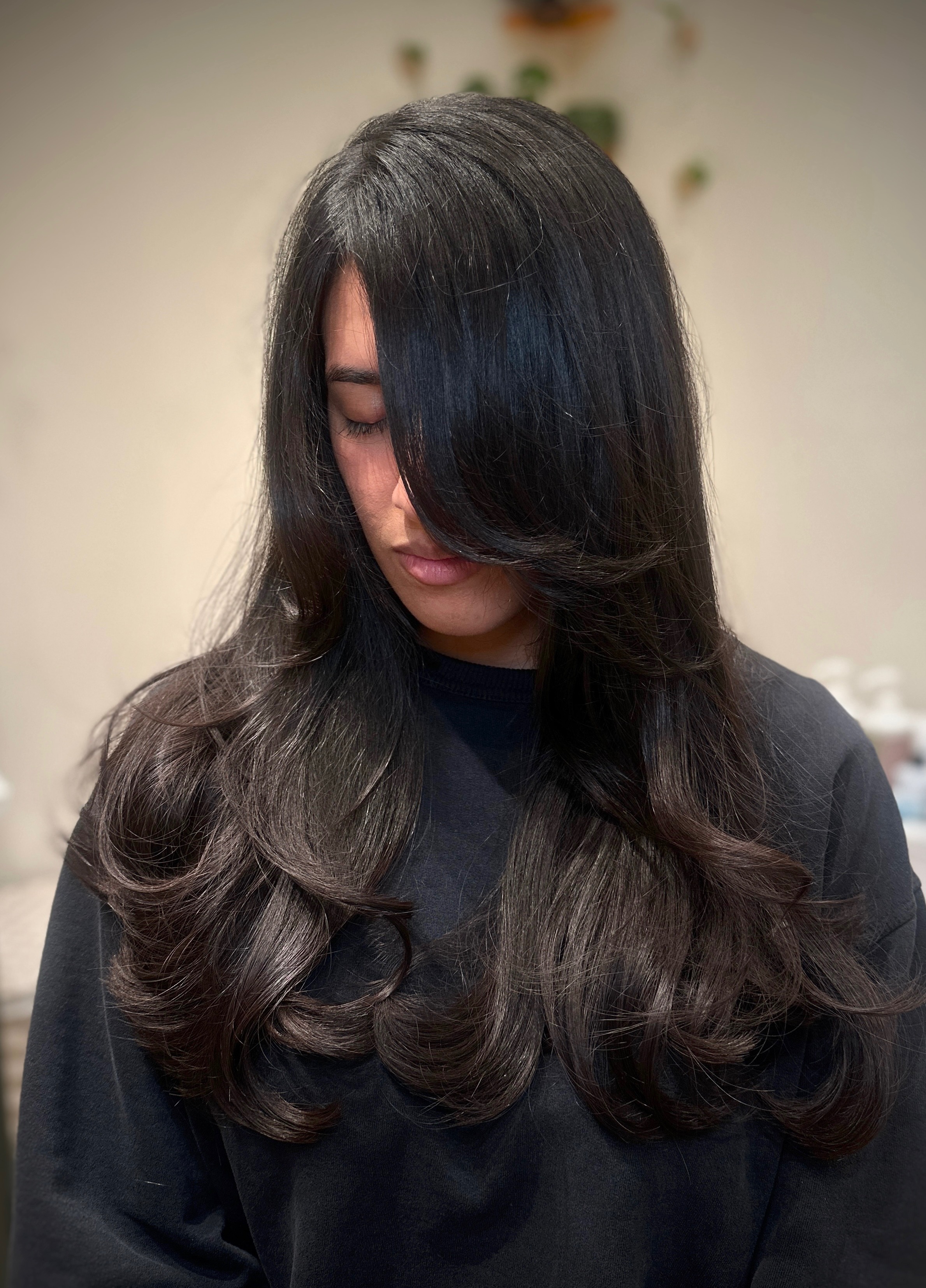 Long butterfly layers with curtain bangs and bouncy blowout on dark hair, front view — layered haircut near Chino Hills, Likha Studio Inland Empire
